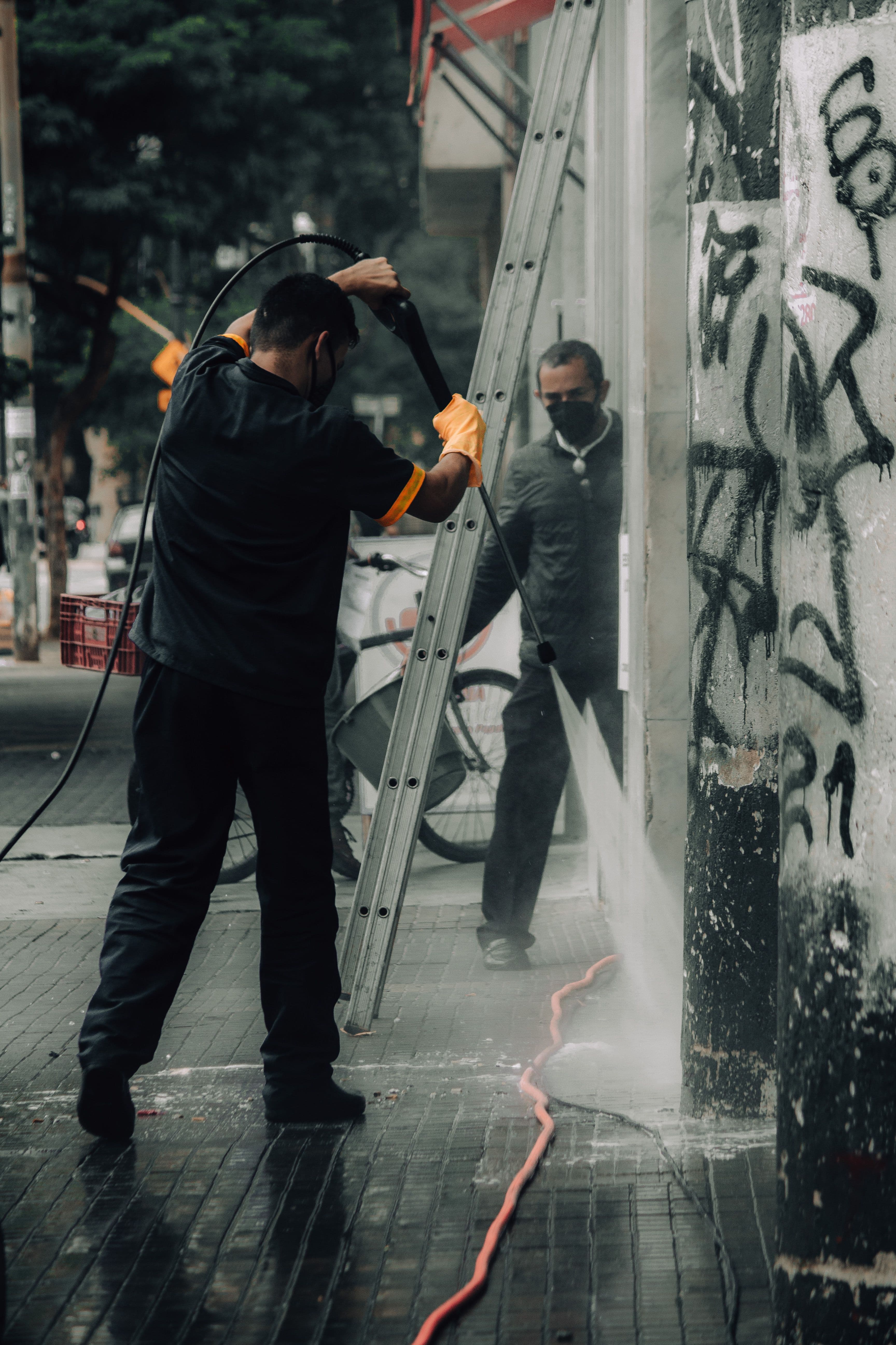 A worker pressure washing graffiti from the exterior wall of a commercial building