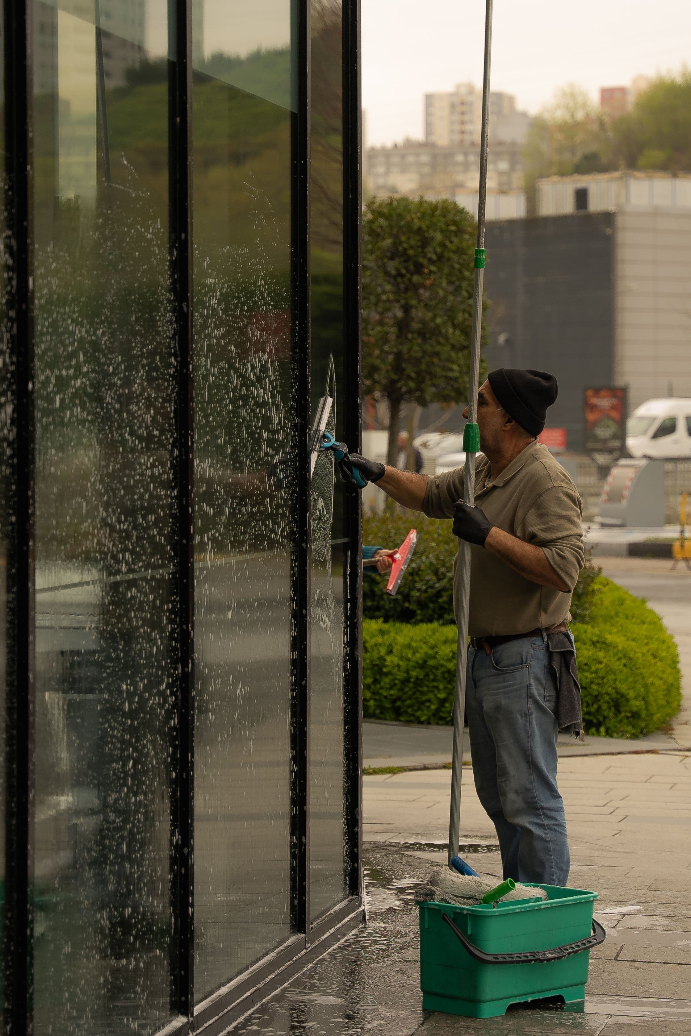 A worker using a squeegee to clean a commercial storefront window
